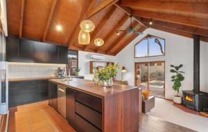 una cucina a pianta aperta con soffitti in legno e una grande isola di Coastal Timber Escape with Pool a Ocean Grove