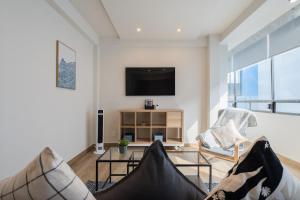 Una sala de estar con televisión, sofá y sillas. en ZIELO BRASIL Historic Center, en Ciudad de México