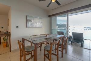 a dining room with a table and chairs and a large window at Amazing Condo Ocean View By Bamboo Skylife in Acapulco