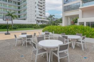 a group of tables and chairs in front of a building at Amazing Condo Ocean View By Bamboo Skylife in Acapulco