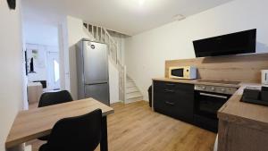 a kitchen with a table and a stainless steel refrigerator at La Pause - Centre-ville in Bourbourg