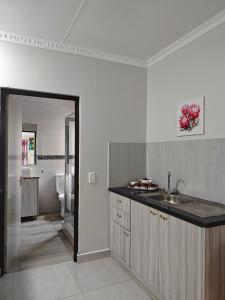 a white kitchen with a sink and a bathroom at Spring Cottage in Walvis Bay