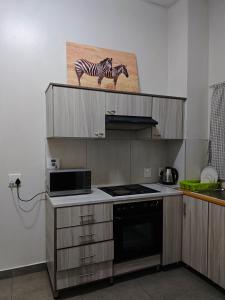 a kitchen with a stove and a picture of a zebra at Spring Cottage in Walvis Bay