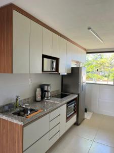 a kitchen with white cabinets and a stainless steel refrigerator at Bioflora 69 Itacimirim in Camacari
