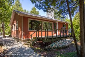 a small house with a porch and a canoe in front of it at Breezy Woods - Tobermory Waterfront in Tobermory