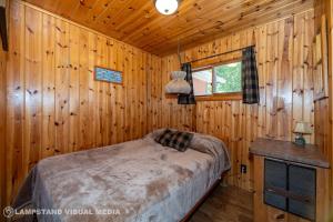 a bedroom with a bed in a wooden cabin at Breezy Woods - Tobermory Waterfront in Tobermory