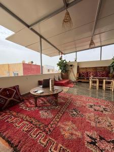 een woonkamer met een rood tapijt en een tafel bij Breeze surf lodge in Tamraght Ouzdar