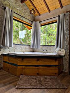 Chalés Recanto Vista do Valle في مونتي فيردي: غرفة بها حوض استحمام خشبي كبير أمام نافذتين +200 صورة