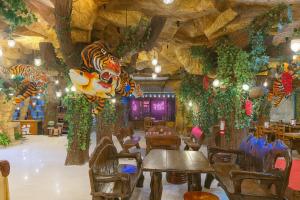a restaurant with tables and chairs in a room with trees at Tiger Complex Inn in Patong Beach