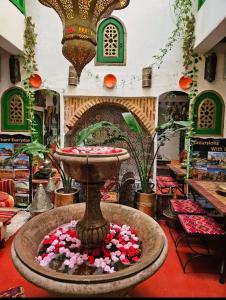 a fountain in the middle of a room with flowers at riad cherif in Marrakech
