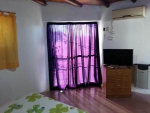 ein Schlafzimmer mit einem lila Vorhang und einem Fernseher in der Unterkunft Departamento Jesica in Colón