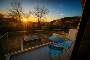 a balcony with a table and two chairs and the sunset at STUNNING VIEW, chambre en forêt proche BORDEAUX in Bouliac