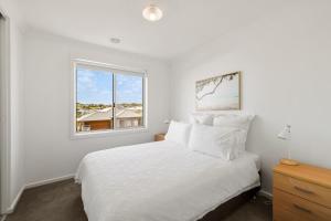 サンレモにあるBay Skies Retreatのベッドと窓のある白い寝室