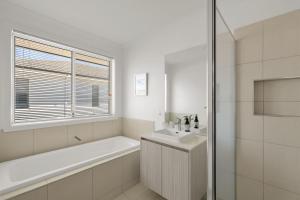 サンレモにあるBay Skies Retreatの浴槽と洗面台のある白いバスルーム +11枚の写真