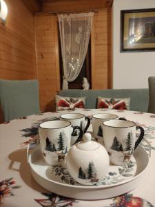 un tavolo con quattro tazze da tè su un piatto di Nowoczesny Domek Góralski a Kielce