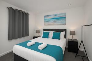 Stylish 2-Bed flat, fast Wi-Fi, Sky & free parking في Buckinghamshire: غرفة نوم بسرير كبير مع وسائد زرقاء وبيضاء