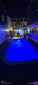 a large blue swimming pool in a building at night at Kitnet in Itaparica Town