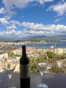 eine Flasche Wein und zwei Weingläser auf einem Felsvorsprung in der Unterkunft T2 avec vue panoramique in Ajaccio