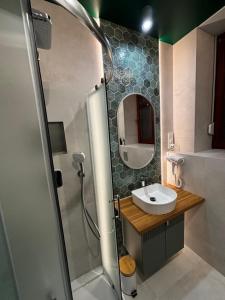 a bathroom with a sink and a shower with a mirror at Rybaki Sauna & Jacuzzi Apartment in Poznań