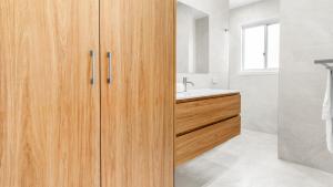 Elizabeth Beach Guest House في Elizabeth Beach: حمام به دواليب خشبية ومغسلة +14 صورة