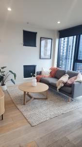 Seffadom apartments Melbourne cbd في ملبورن: غرفة معيشة مع أريكة وطاولة قهوة