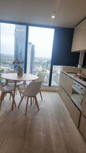 Seffadom apartments Melbourne cbd في ملبورن: مطبخ مع طاولة وكراسي في غرفة مع نوافذ كبيرة