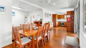 Elizabeth Beach Guest House في Elizabeth Beach: غرفة طعام ومطبخ مع طاولة وكراسي خشبية