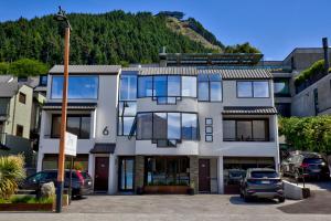 Queenstown House Lakeside في كوينزتاون: مبنى أبيض فيه سيارات تقف في موقف للسيارات