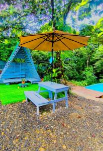 una mesa de picnic con una sombrilla y un banco en Monstera Forest Lodge, en Fortuna