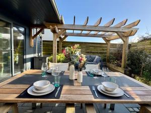 a wooden table with plates and wine glasses on a patio at Uno Carbis Bay - Boutique Luxury Accommodation in Carbis Bay