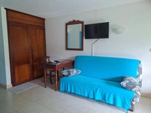 - un canapé bleu dans une pièce avec une table et un miroir dans l'établissement Ty Alice, à Sainte-Anne