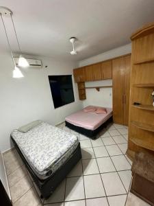 two beds in a room with a tv at Pousada Fortaleza da Enseada in Bertioga