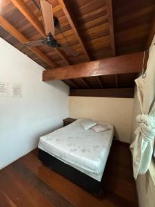 a small bed in a room with a ceiling at Pousada Fortaleza da Enseada in Bertioga