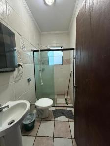 a bathroom with a shower and a toilet and a sink at Pousada Fortaleza da Enseada in Bertioga