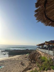 una playa con un edificio y el océano en Black Pearl surf yoga and skate house, en Tamraght Ouzdar