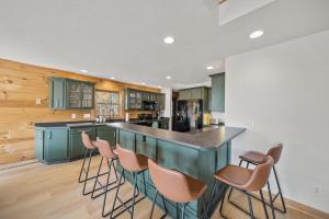 a kitchen with green cabinets and a bar with stools at Sugar View Chalet in Banner Elk