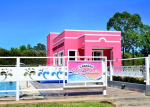 um edifício cor-de-rosa com uma placa à frente. em Cabañas La Soñada em Chajarí