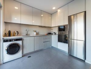 eine Küche mit weißen Schränken und einer Waschmaschine und einem Trockner in der Unterkunft Modern & Quiet 2BR 2 Baths 4 Balconies & Lift in Ílhavo