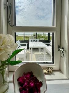 a vase filled with purple flowers next to a window at 180 Degree View Over Sebbersund Fjord in Nibe