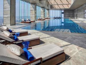 a large swimming pool with benches and tables in a building at Pullman Huizhou Kaisa in Huizhou