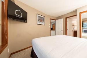 a bedroom with a bed and a tv on the wall at Aspens Lodge 220 by Outpost Whistler in Whistler