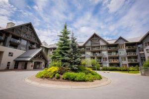 a large apartment building with a pine tree in front of it at Aspens Lodge 220 by Outpost Whistler in Whistler
