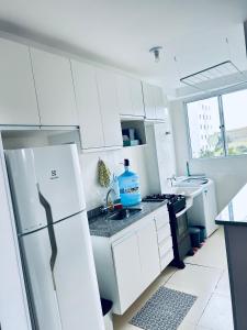 Una cocina blanca con fregadero y refrigerador. en Cond Millenium residênce, en Juiz de Fora
