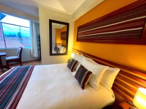 a bedroom with a large white bed with pillows at Hotel Chinchero Boutique & Tours in Chinchero