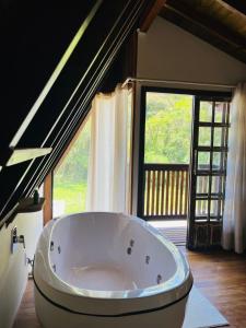 a large bath tub in a room with a large window at Cabana na Natureza Com Hidro - Baoba Suites in Bombinhas
