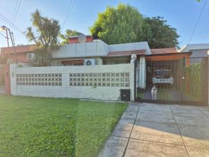 Nel's Casa Hostel A 15 minutos de Aeropuerto Ezeiza في مونتي غراندي: حاجز امام بيت وخلفه كلب