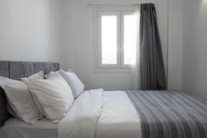 Una cama blanca con almohadas blancas y una ventana. en Casa Poco, 150 meters from Ornos Beach, en Ornos