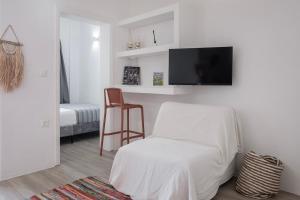 Una sala de estar blanca con una silla y un televisor de pantalla plana. en Casa Poco, 150 meters from Ornos Beach, en Ornos