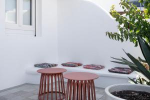 Un patio con dos taburetes junto a una pared blanca. en Casa Poco, 150 meters from Ornos Beach, en Ornos