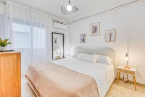 a white bedroom with a bed and a television at Hanami Avenida de España Beach Front - Mountain View in Estepona